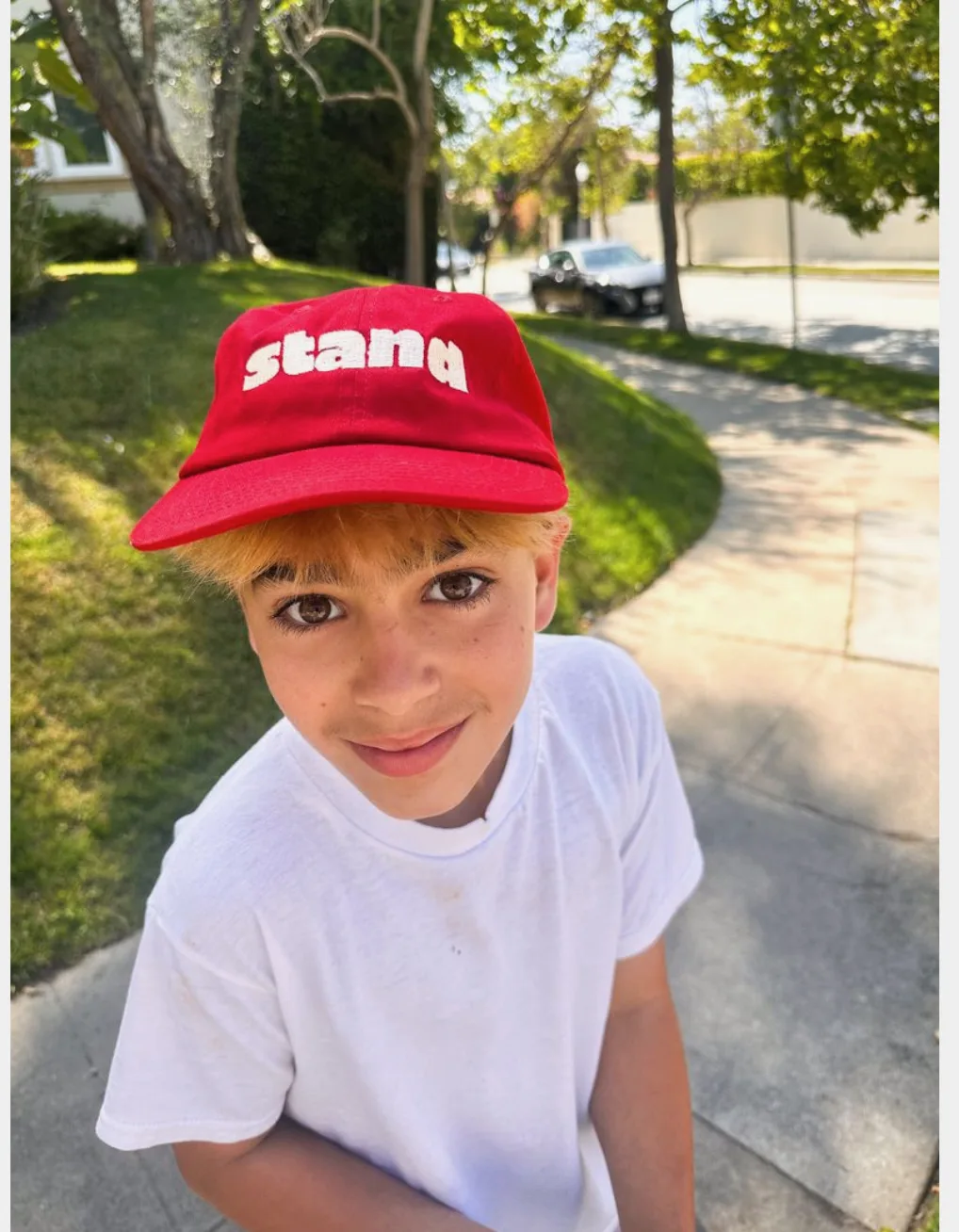 Stand kid in a red Stand cap on a sidewalk